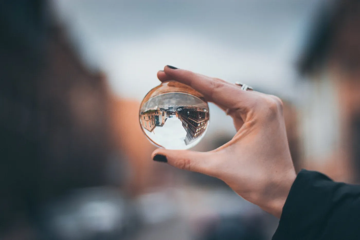 A hand holding a glass ball that shows the street upside down